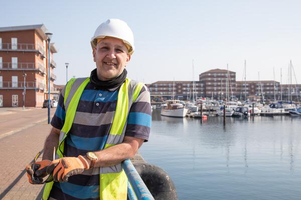 Builder standing by a marina with water and boats